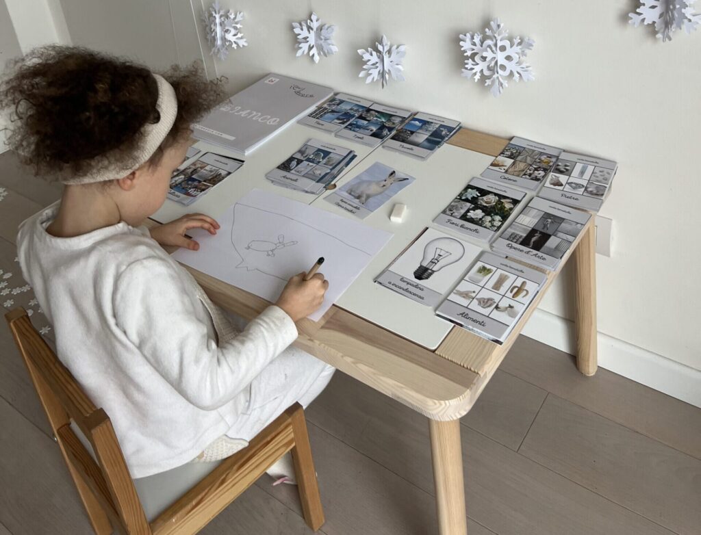 Bambina che utilizza le carte delle nomenclature montessoriane per le attività sui colori del percorso Il Bel Lavoro